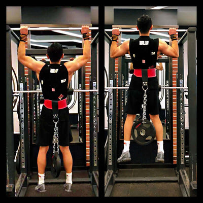 Athlete performing weighted pull-ups with a leather lifting belt and chain ring in a gym setting.